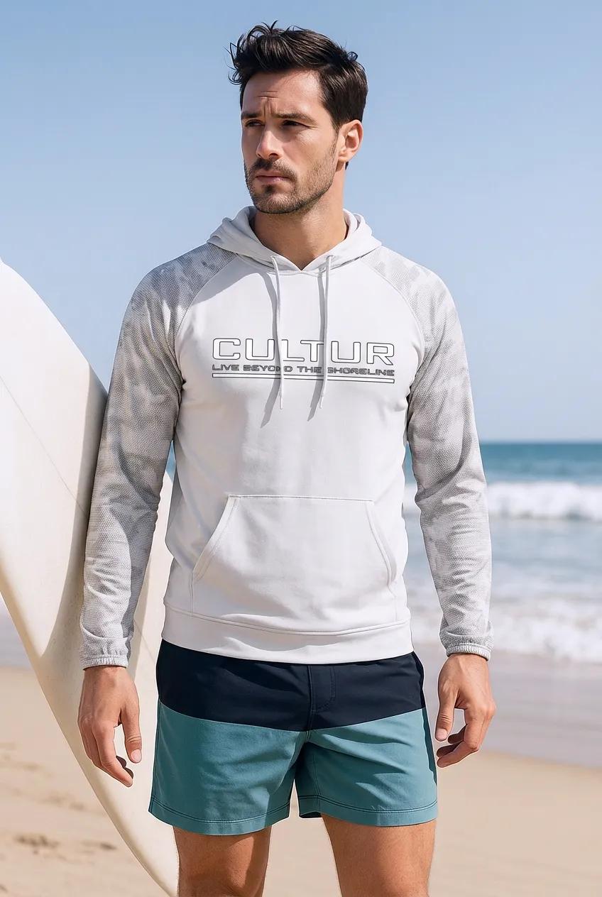 Man wearing a hoodie with 'Cultur' branding on a beach