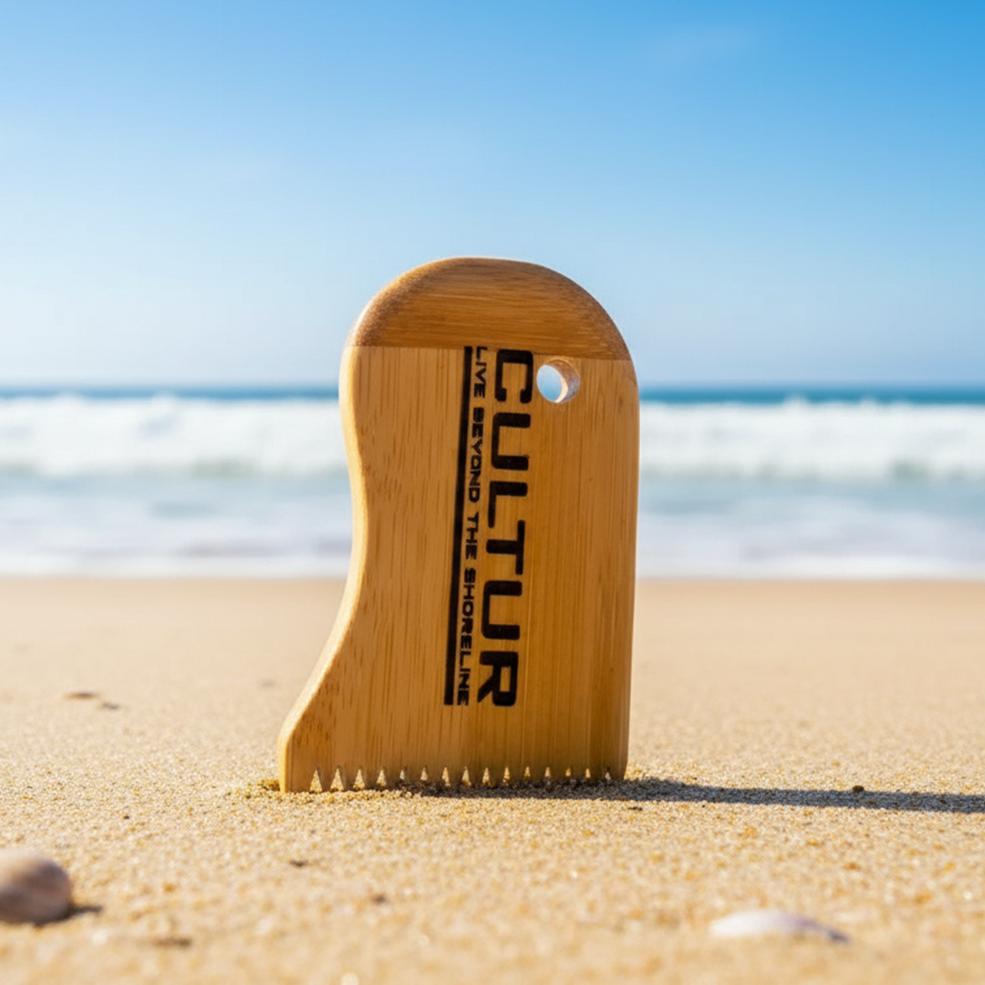 Wooden surf wax tool with 'Cultur' branding on a sandy beach with ocean in the background