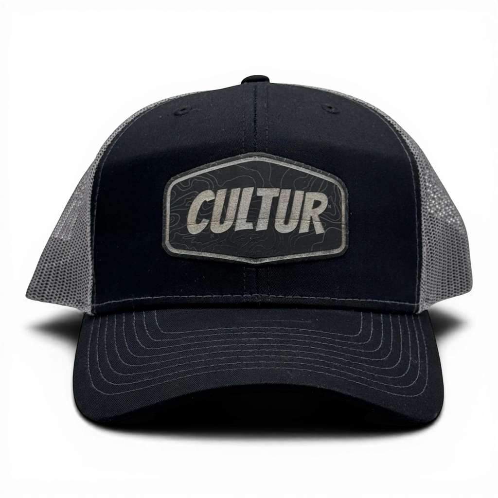 CULTUR black trucker hat with grey mesh back and embroidered CULTUR Topo patch.