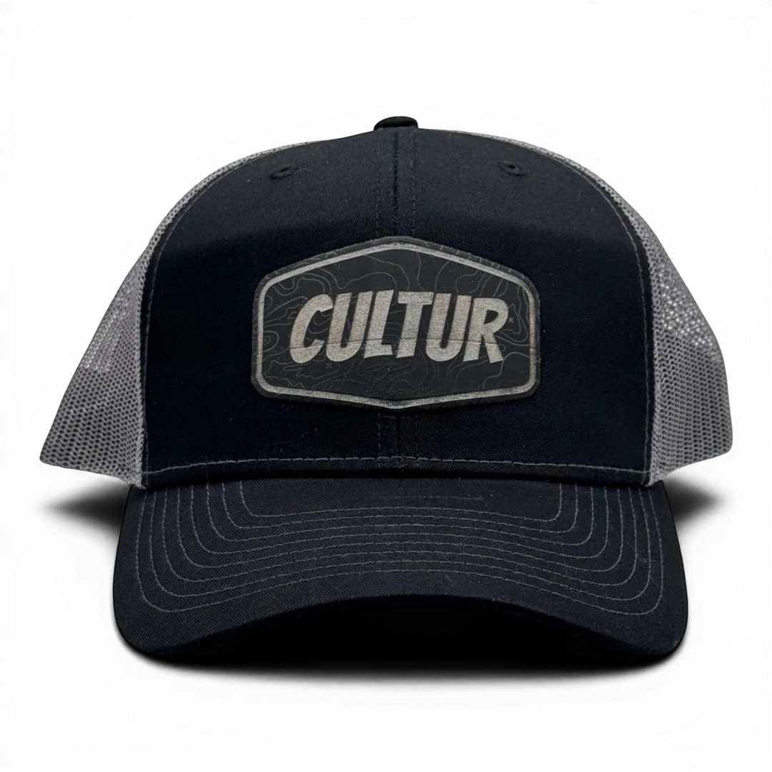 CULTUR black trucker hat with grey mesh back and embroidered CULTUR Topo patch.
