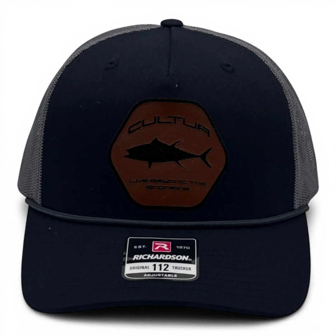 CULTUR black trucker hat with grey mesh back and a brown hexagonal patch featuring a black tuna silhouette and text.
