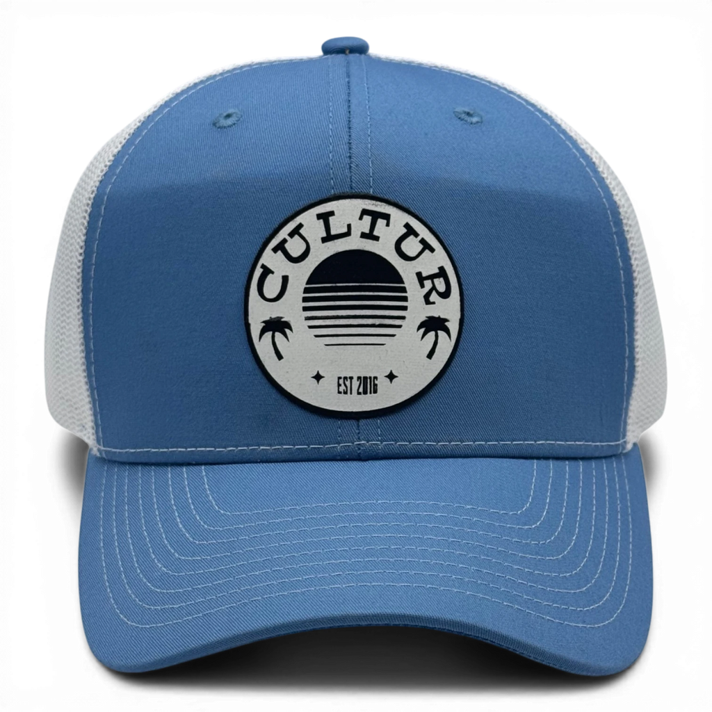 CULTUR blue trucker hat with white mesh back and circular patch featuring a sunset and palm trees.