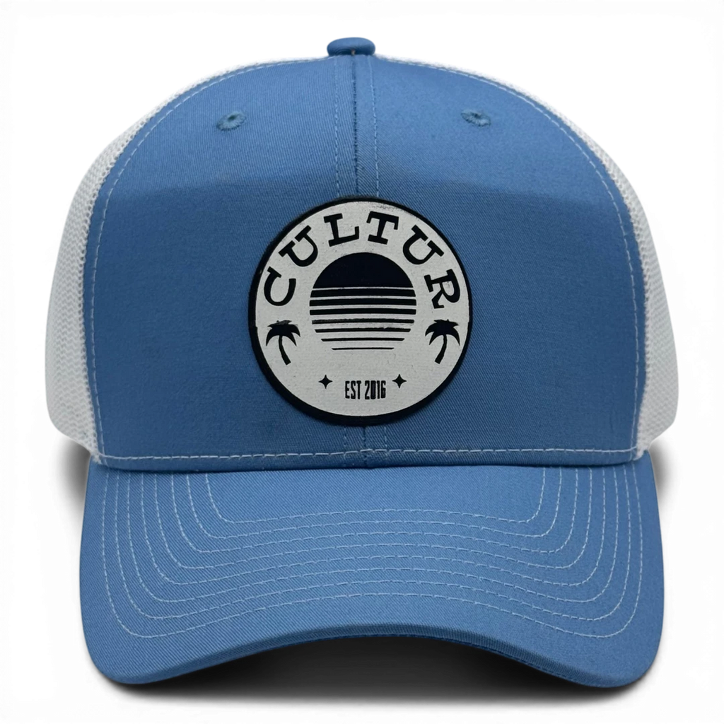 CULTUR blue trucker hat with white mesh back and circular patch featuring palm trees and a sunset design.