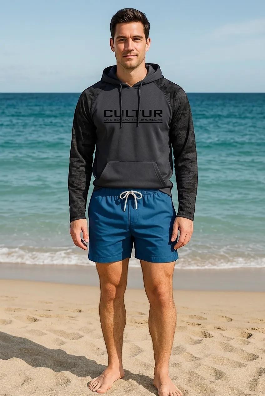 CULTUR graphite microfiber performance hoodie with black camo sleeves and drawstring hood, worn by a man on a beach.