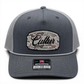 CULTUR grey trucker hat with white mesh back and a camouflage patch featuring the CULTUR logo.