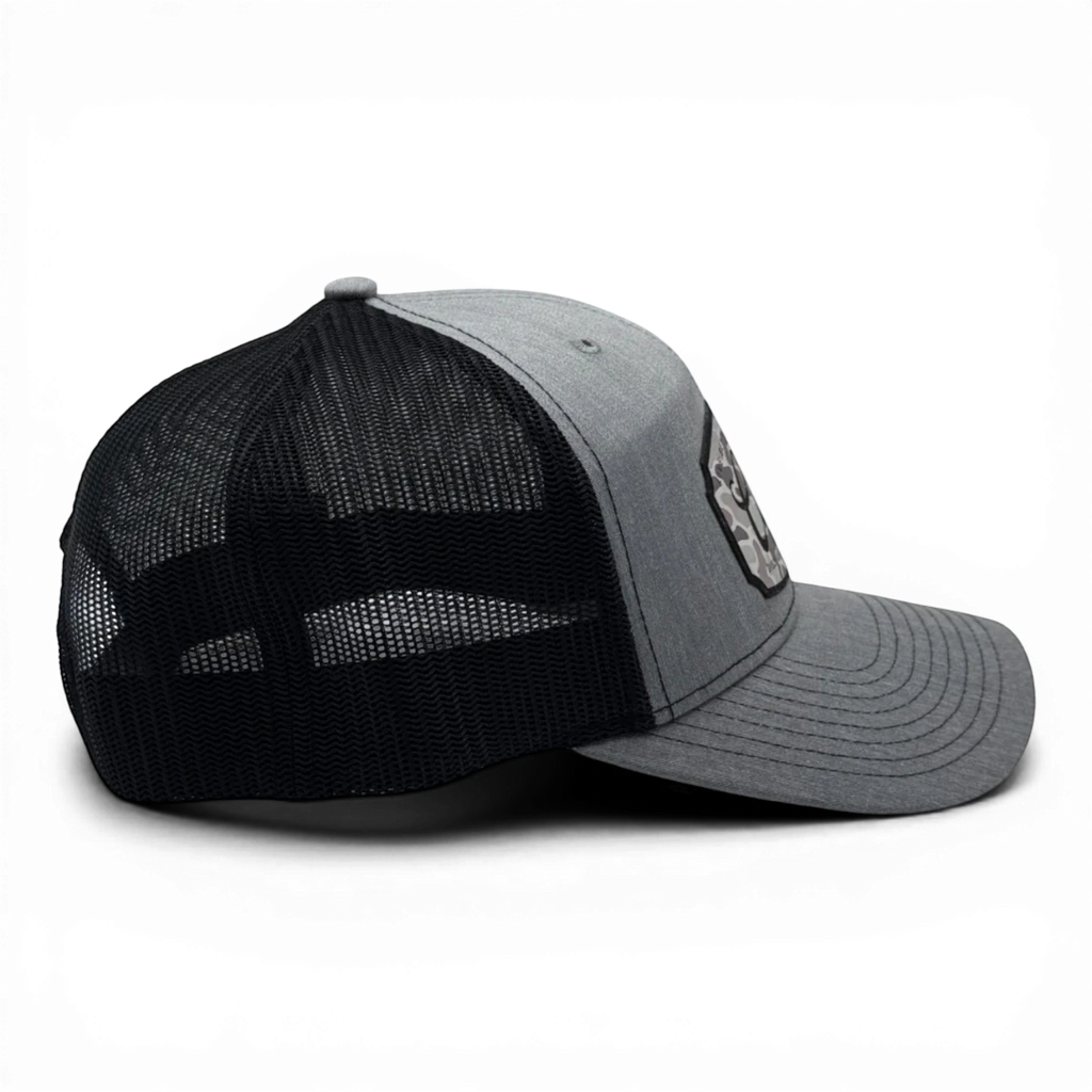CULTUR grey trucker hat with black mesh back and a CULTUR camo patch on the front.