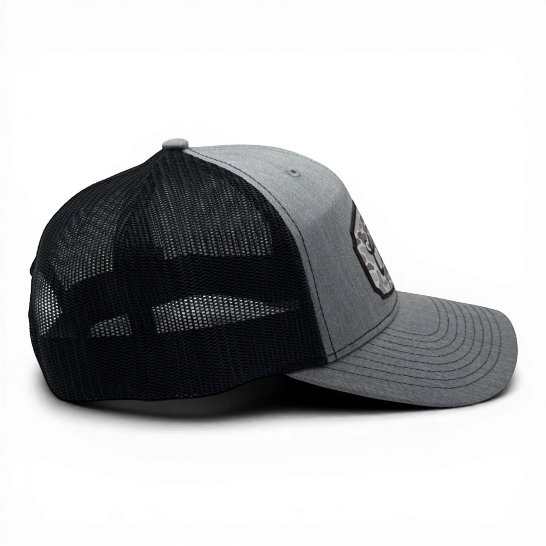 CULTUR grey trucker hat with black mesh back and a CULTUR camo patch on the front.