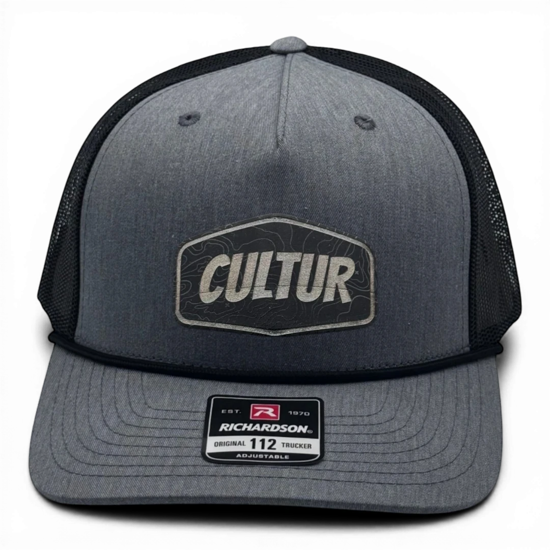 CULTUR grey trucker hat with black mesh back and embroidered topo patch logo.