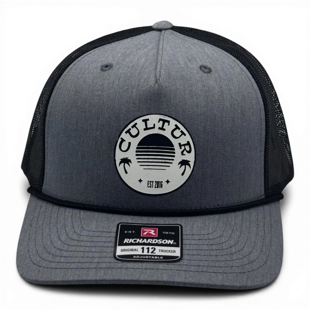 CULTUR grey trucker hat with black rope and black mesh back and circular patch featuring palm trees and a sunset.