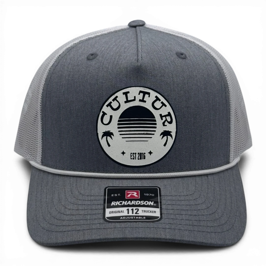 CULTUR grey trucker hat with white rope and mesh back and circular patch featuring a sunset and palm trees.