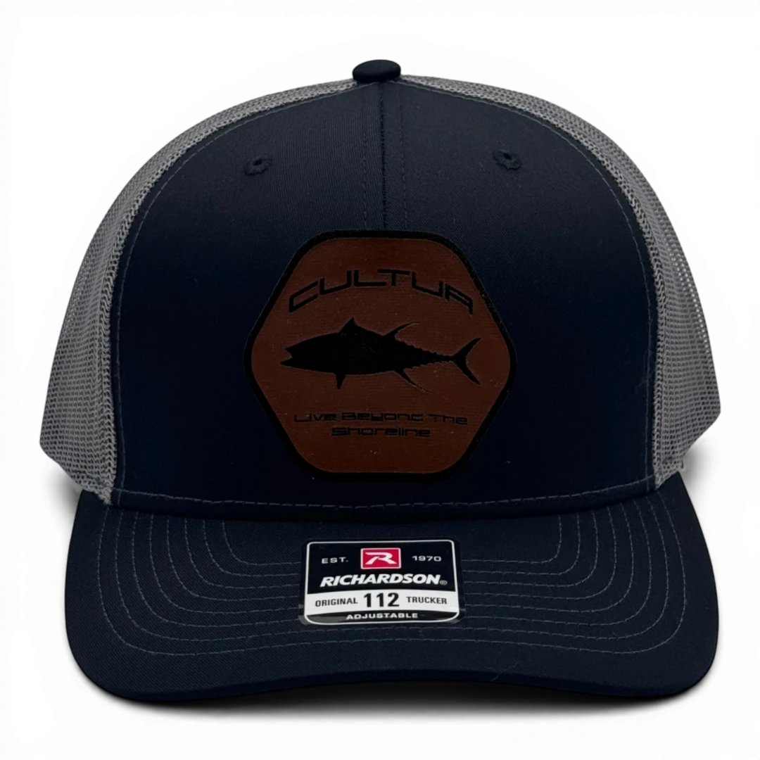 CULTUR black trucker hat with grey mesh back and a brown hexagonal patch featuring a black tuna silhouette and text.