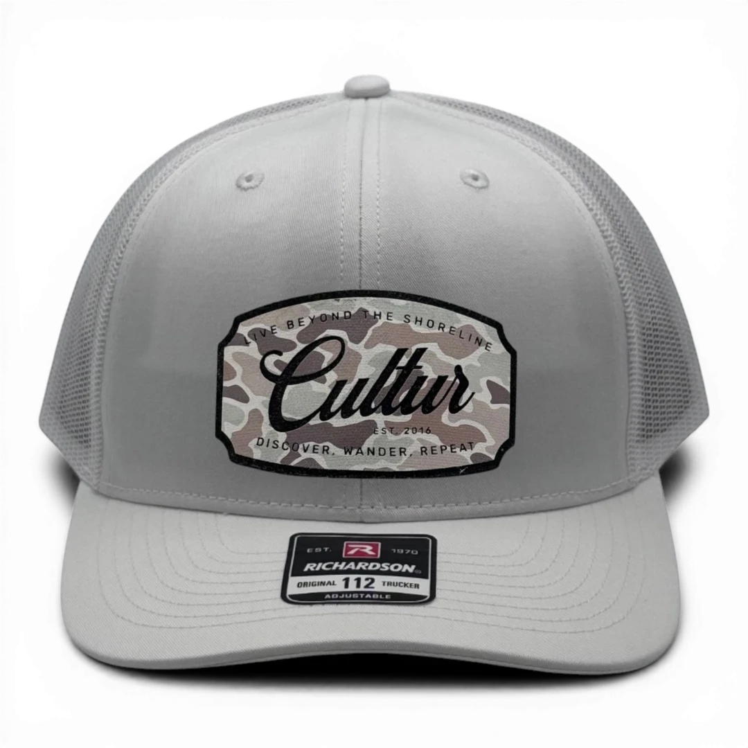 CULTUR white trucker hat with a camouflage patch featuring the brand name
