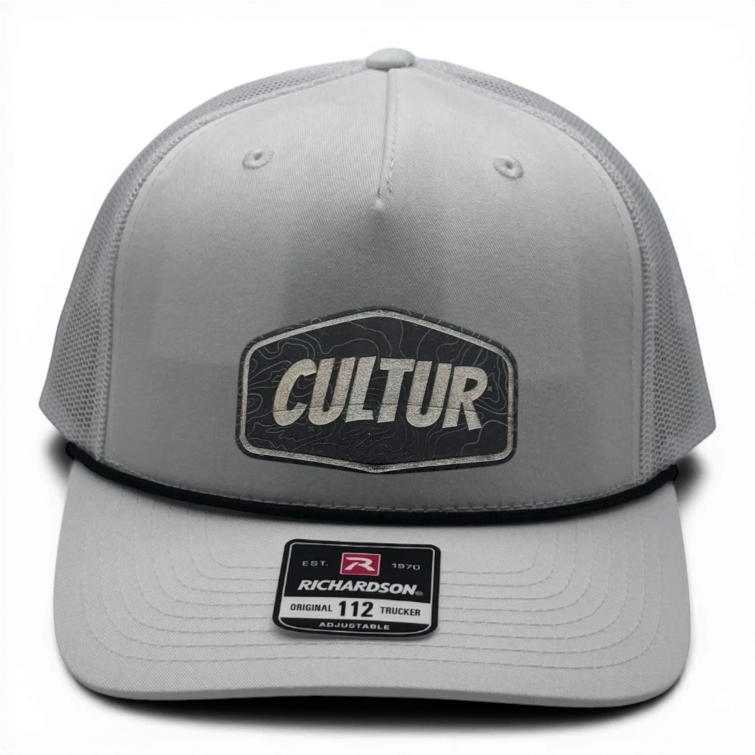 CULTUR white trucker hat with black rope and mesh back and embroidered CULTUR Topo patch. Adjustable fit.